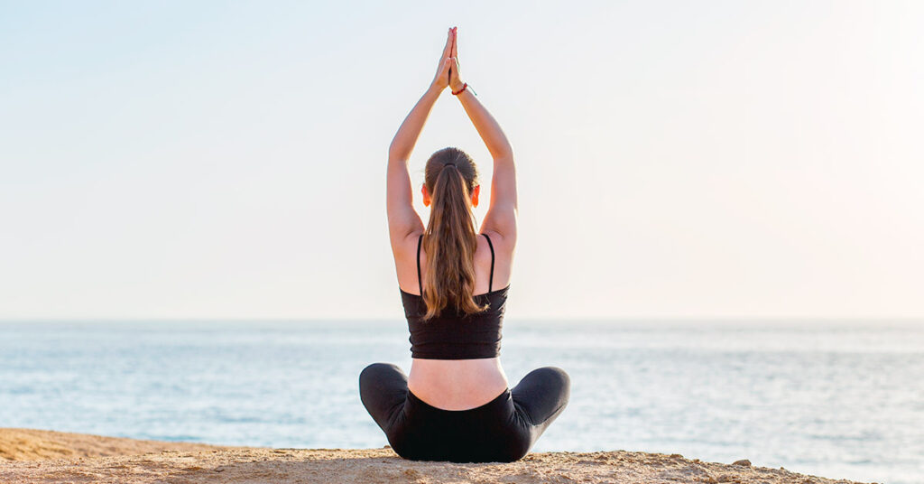 Imagen mujer haciendo yoga en la playa 